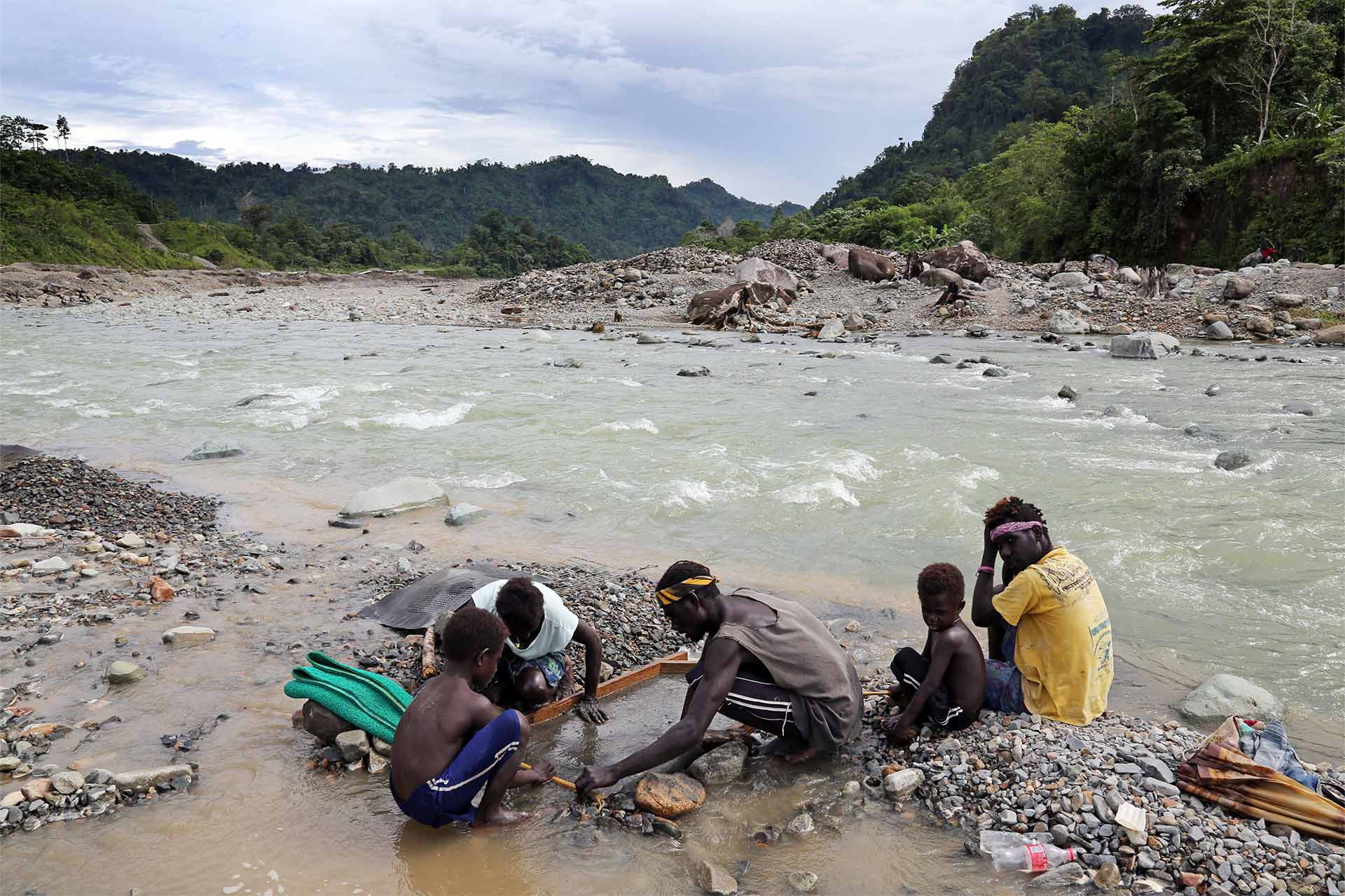 A family panning for gold in polluted waters
